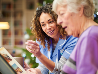 Elderly woman suffering with dementia looking through a memory book with her care worker in a home setting.