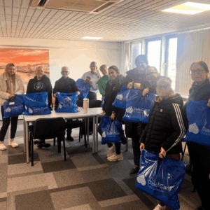 Group of our new starters with their new Dale Care uniforms in branded blue carrier bags. All stood in a group and smiling towards the camera.