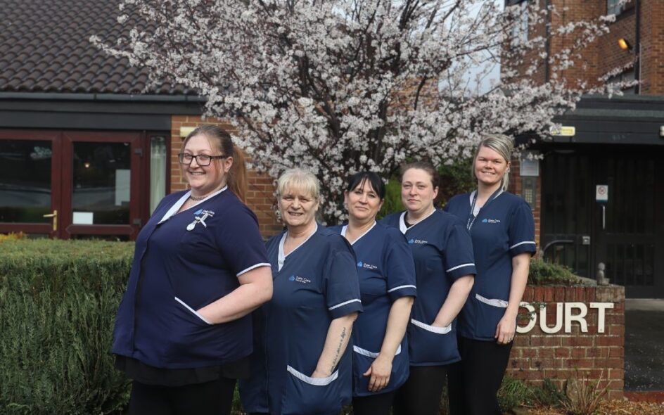 Pictured is five of Dale Care's caring care workers outside, stood together and smiling towards the camera in their navy uniforms.